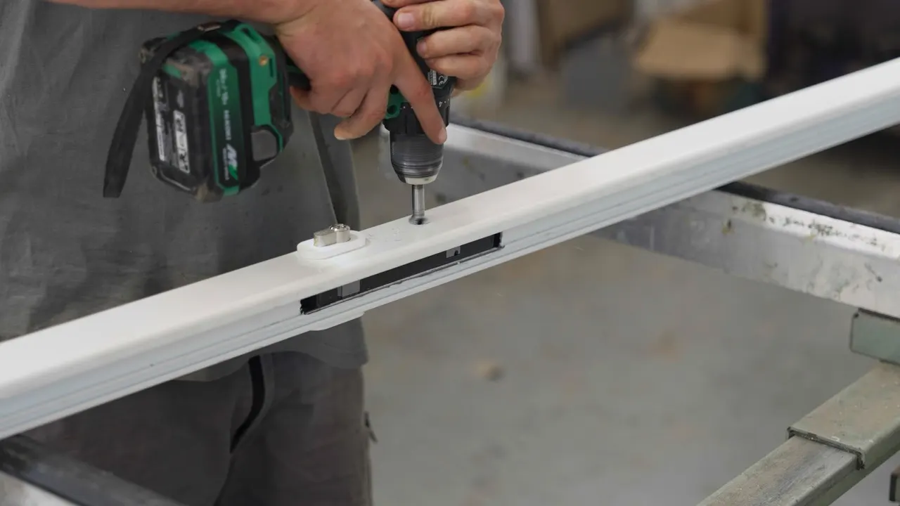 A white profile being screwed together at the bench